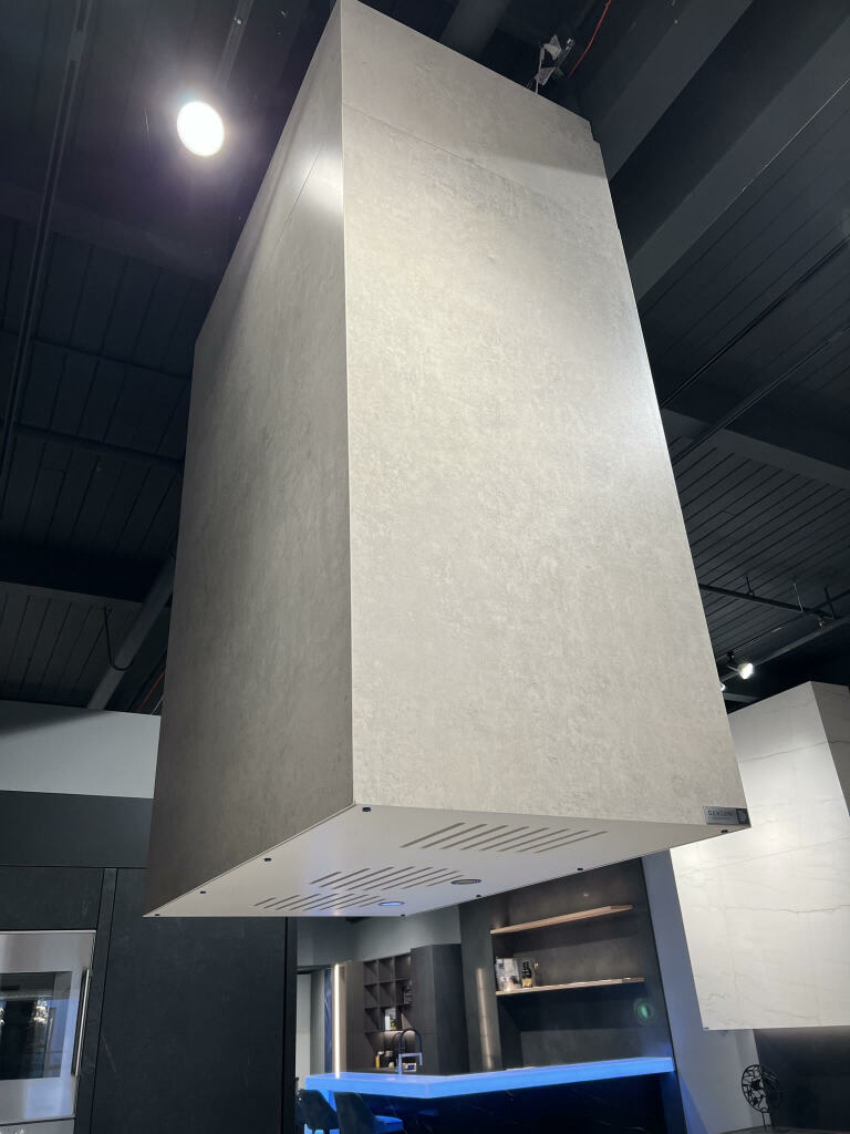 A Stone Hood wrapped with Dekton refers to a specific design feature in a kitchen where a stone hood is covered or wrapped with Dekton, an engineered stone material known for its durability and versatility. A Stone Hood wrapped with Dekton combines the natural beauty of stone with the durability and practicality of Dekton. This design elevate the look of the kitchen and provide a functional and visually appealing focal point.